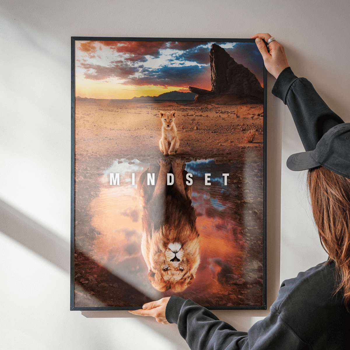 Frau hängt Mindset Poster mit schwarzem Rahmen an die Wand – Stilvolles Motivationsbild für modernes Interieur.